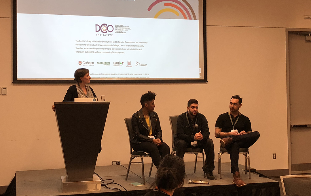 Four attendees engage in a panel discussion in front of an audience.