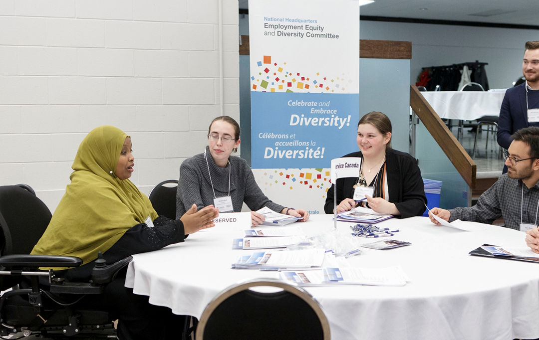 Attendees engage in a group discussion around a table.