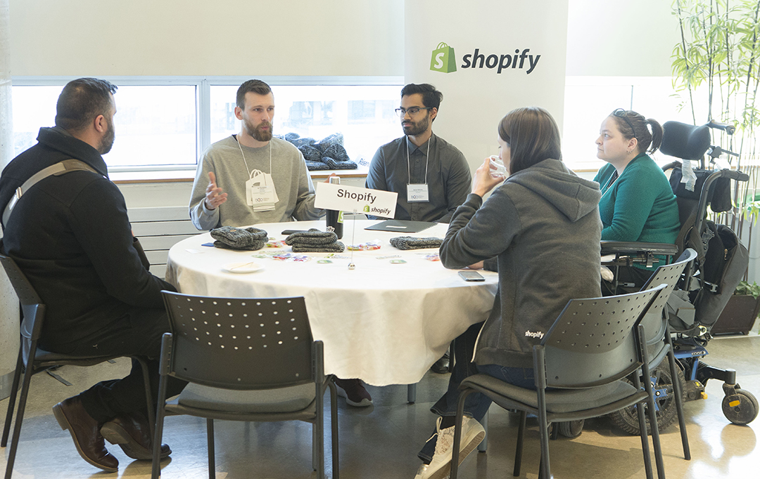 A group of students engages with Shopify team members.